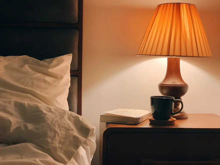 Quarto com luz baixa vinda de um abajur ao lado da cama