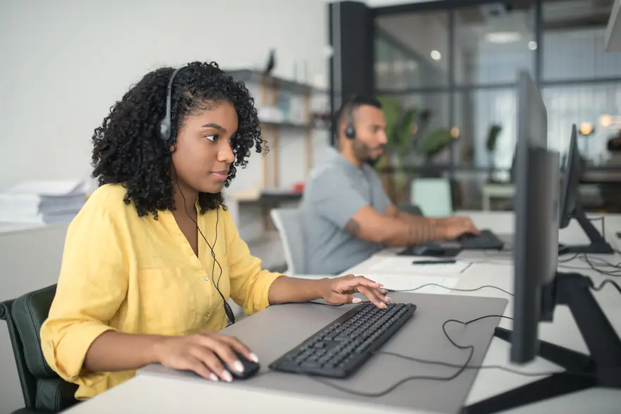 Atendente com fone de ouvido trabalhando no computador em um escritório claro
